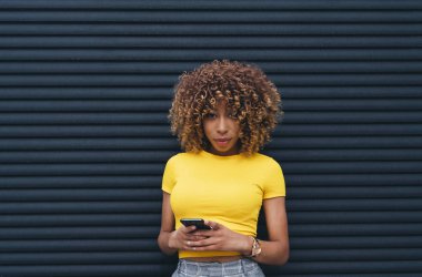 Cep telefonu kullanan afro saçlı güzel bir kadın..