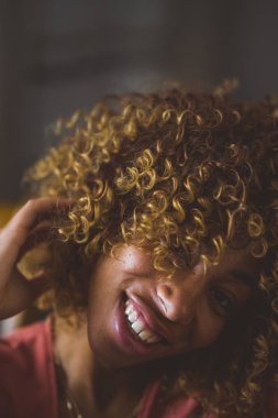 Selective focus of a woman smiling looking up with a beautiful curly hair.