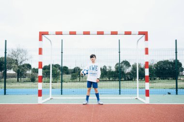 Kolunda top olan futbolcu çocuğun portresi.