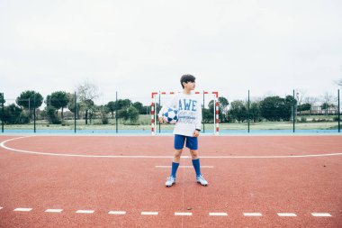 Futbolcu çocuk topu elle tutuyor.