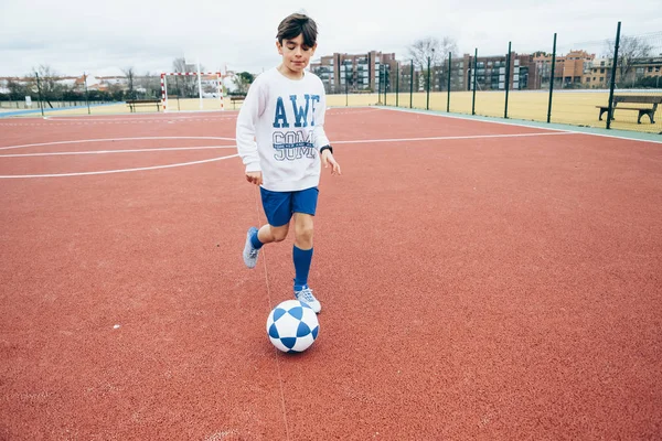Хлопчик грає у футбол на відкритому повітрі з червоним тлом — стокове фото