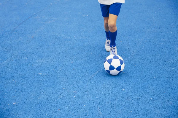 Pequeño niño irreconocible jugando fútbol de fondo azul — Foto de Stock