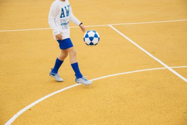 Sarı sahada futbol oynayan çocuk.