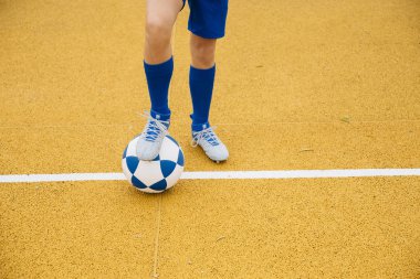 Sarı arka planda futbol oynayan tanınmayan küçük çocuk.