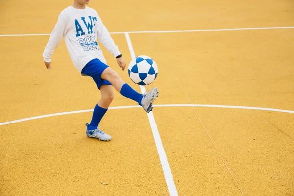 Хлопчик грає у футбол на жовтому дворі — стокове фото