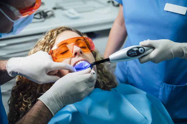 Dokter gigi memeriksa pasien dengan sinar UV — Stok Foto