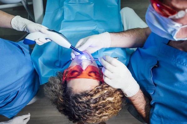Dokter gigi memeriksa pasien dengan sinar UV — Stok Foto