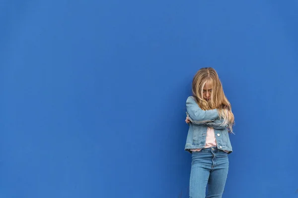 Klein boos blond meisje met blauwe achtergrond — Stockfoto