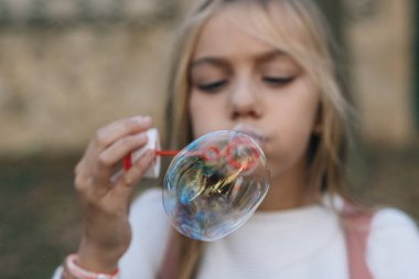 Küçük kız sabun köpüğü üflüyor