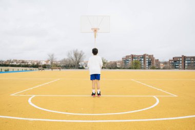 Sarı basketbol sahasında oynayan genç bir çocuk..
