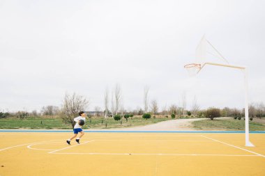 Sarı basketbol sahasında oynayan genç bir çocuk..