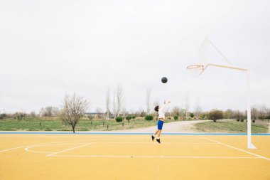 Sarı basketbol sahasında oynayan genç bir çocuk..
