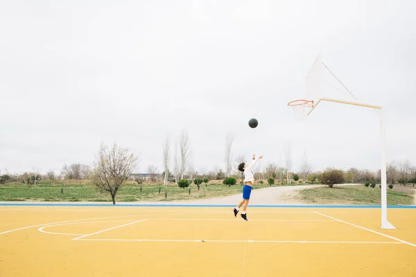 Junge spielt auf gelbem Basketballplatz im Freien. — Stockfoto