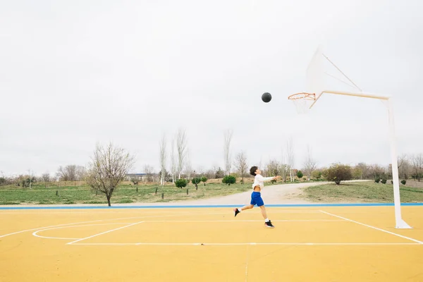 Jonge jongen spelen op gele basketbalveld outdoor. — Stockfoto