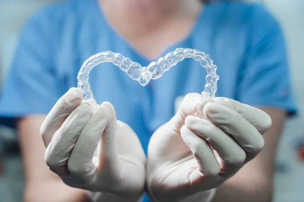 Médica feminina segurando dois alinhadores dentários transparentes em forma de coração — Fotografia de Stock