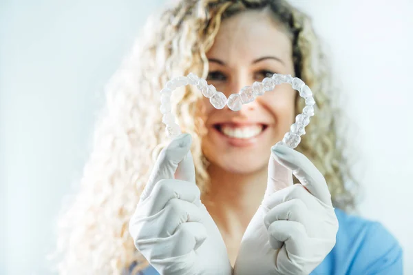 Médica feminina segurando dois alinhadores dentários transparentes em forma de coração — Fotografia de Stock