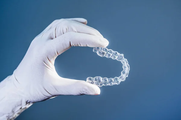 Mano del doctor sosteniendo un alineador dental transparente —  Fotos de Stock