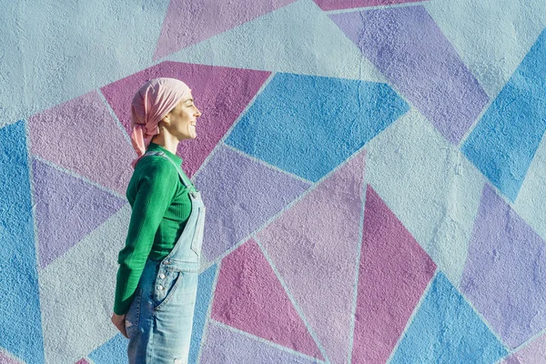 Mulher com lenço de cabeça combate o câncer em uma parede colorida — Fotografia de Stock