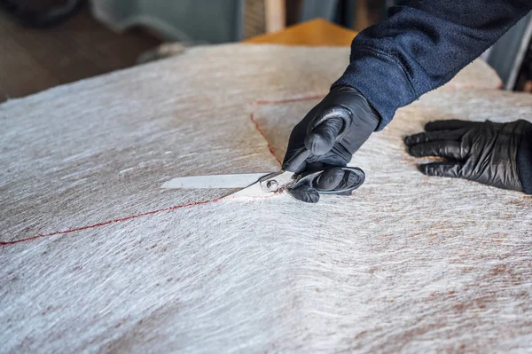 62 jaar oude man snijden vezel met een schaar in de werkplaats. — Stockfoto