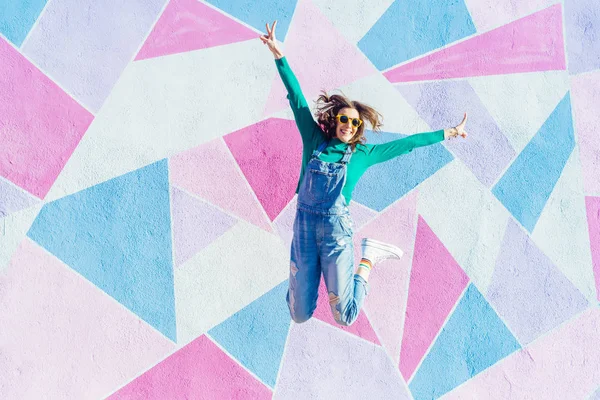 Mujer saltando delante de un fondo colorido — Foto de Stock