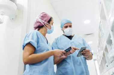 Doktorlar hastane koridorunda cep telefonu kullanıyorlar. Tıbbi konsept