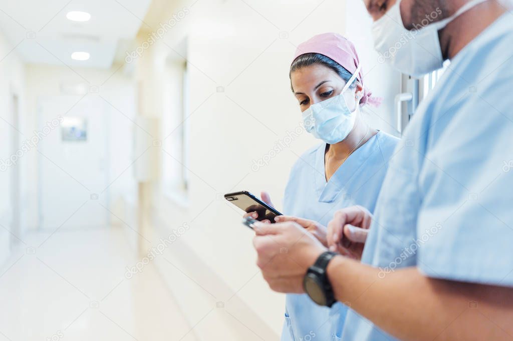 Doctors using cell phones in the hospital corridor. Medical concept