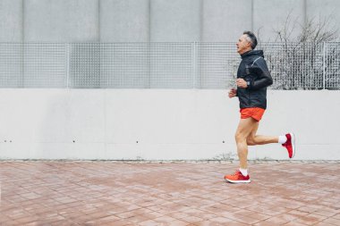 Emekli kıdemli adam koşuyor ve egzersiz yapıyor.