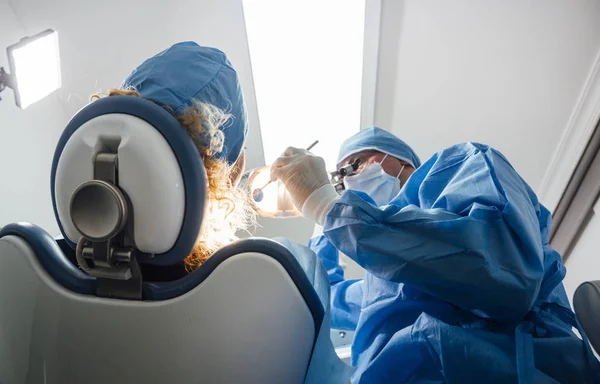 Dentista durante uma intervenção dentária com um paciente. Conceito de clínica odontológica . — Fotografia de Stock