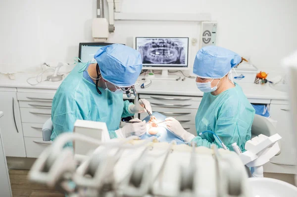 Dentista durante uma intervenção dentária com um paciente. Conceito de clínica odontológica . — Fotografia de Stock