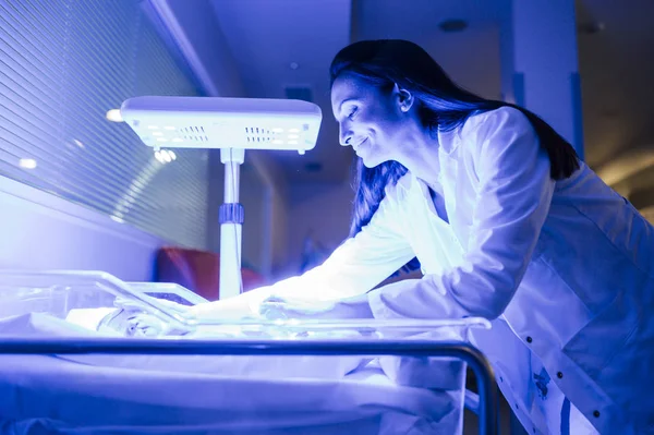 Родители нежно касаются хрупкого новорожденного в неонатальном инкубаторе — стоковое фото