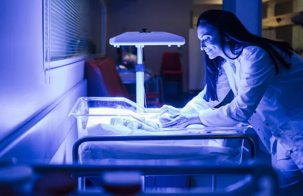 Padres tocando suavemente al recién nacido frágil en la incubadora neonatal —  Fotos de Stock