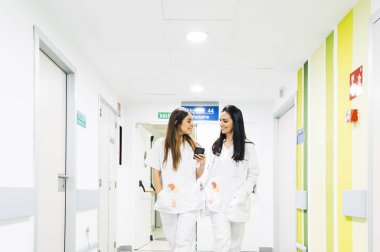 Hemşire ve doktor hastane koridorunda yürüyorlar. -