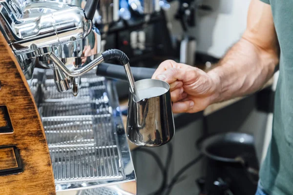 Ovanifrån av händer barista virvlande mjölk i kanna med kaffebryggare ångstav — Stockfoto