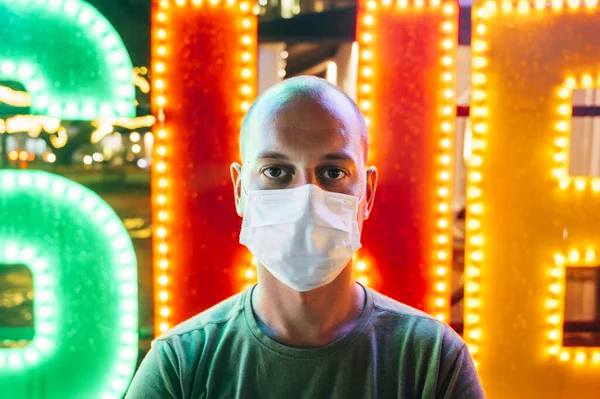 Man with mask and colorful lights in background looking at camera. Virus concept