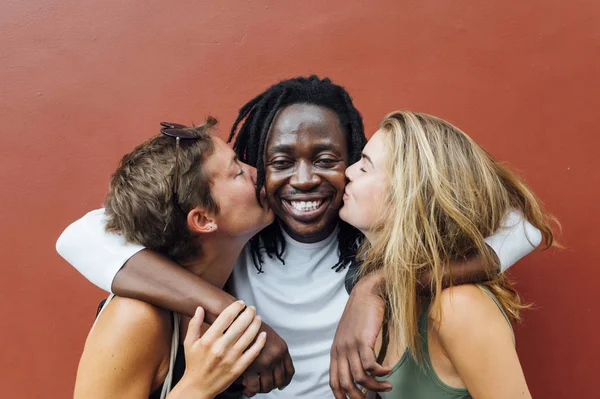 Two women kissing the African man