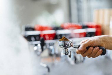 Espresso hazırlarken portafilter alıcısının elinde tuttuğu adamın ayrıntıları.