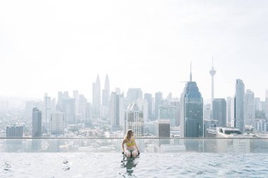 Sonsuzluk havuzundan Kuala Lumpur şehrini izleyen bir kadın.