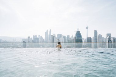 Sonsuzluk havuzundan Kuala Lumpur şehrini izleyen bir kadın.