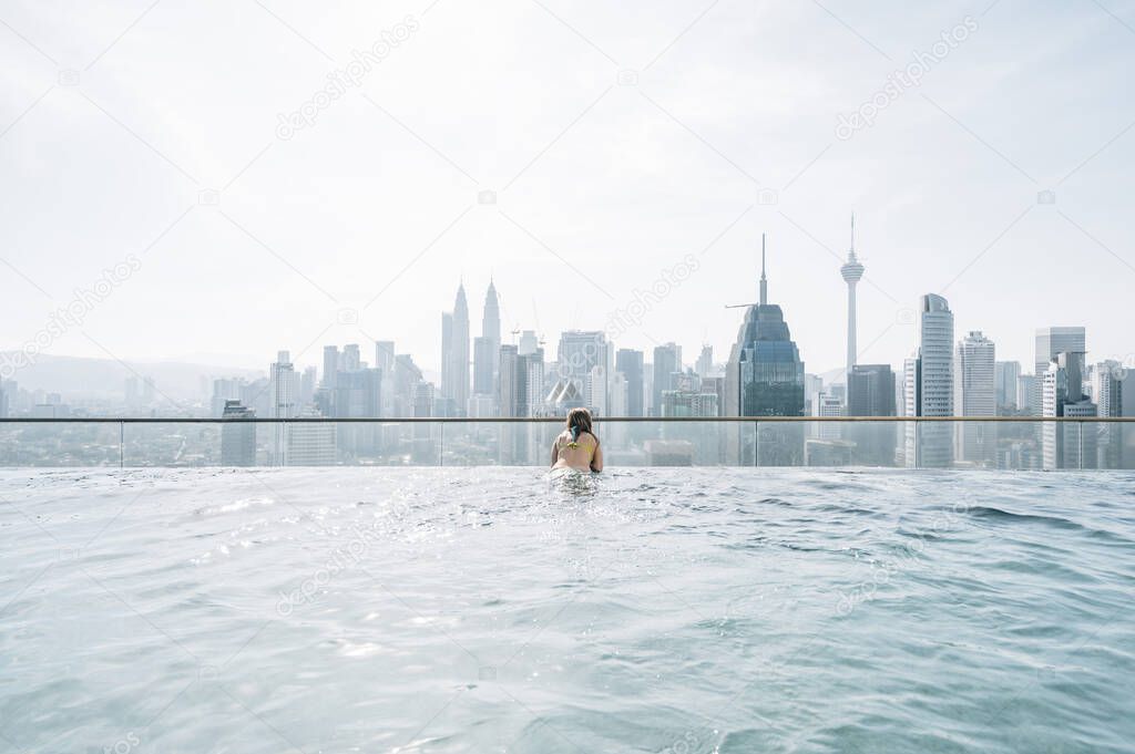 Woman observing the city of Kuala Lumpur from the infinity pool