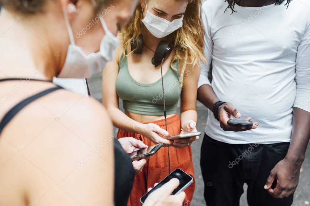 Group of four people with mask and smartphone in the street