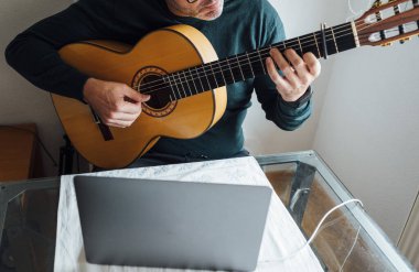 Adam internette gitar çalmayı öğreniyor.