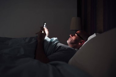 Adam uyumak yerine telefonunu kullanıyor. Teknoloji bağımlılığı.