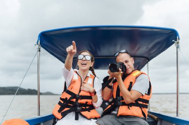 Turistler botta can yeleğiyle fotoğraf çekiyorlar.