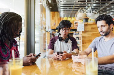 Restorana cep telefonu kullanan çok ırklı arkadaş grubu. Arkadaşlık kavramı