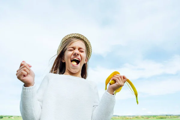 Ξανθό Κοριτσάκι Τρώει Μια Μπανάνα Στο Χωράφι — Φωτογραφία Αρχείου