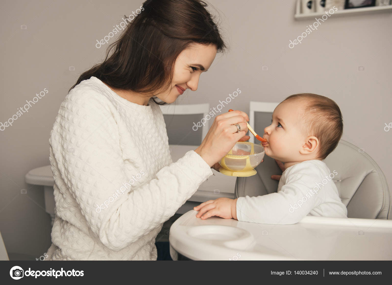 Mom feeding her baby girl by 140034240