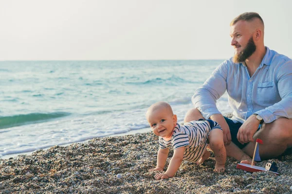Pappa med pojke vilar på stranden — Stockfoto