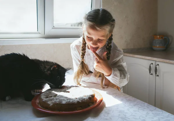 Niña alimentando a un gato negro — Foto de Stock