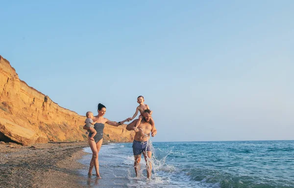 Семья с детьми, гуляющими по морскому побережью . — стоковое фото