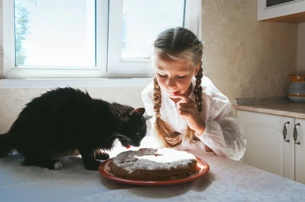 Niña alimentando a un gato negro Imagen de archivo